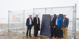 A group of men with hardhats on in front of a solar panel