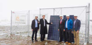 A group of men with hardhats on in front of a solar panel