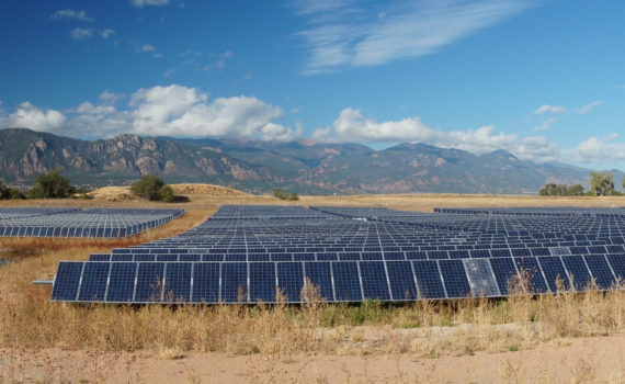 Wide shot of a solar farm in front of mountains