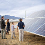 Group of people standing right by a solar panel