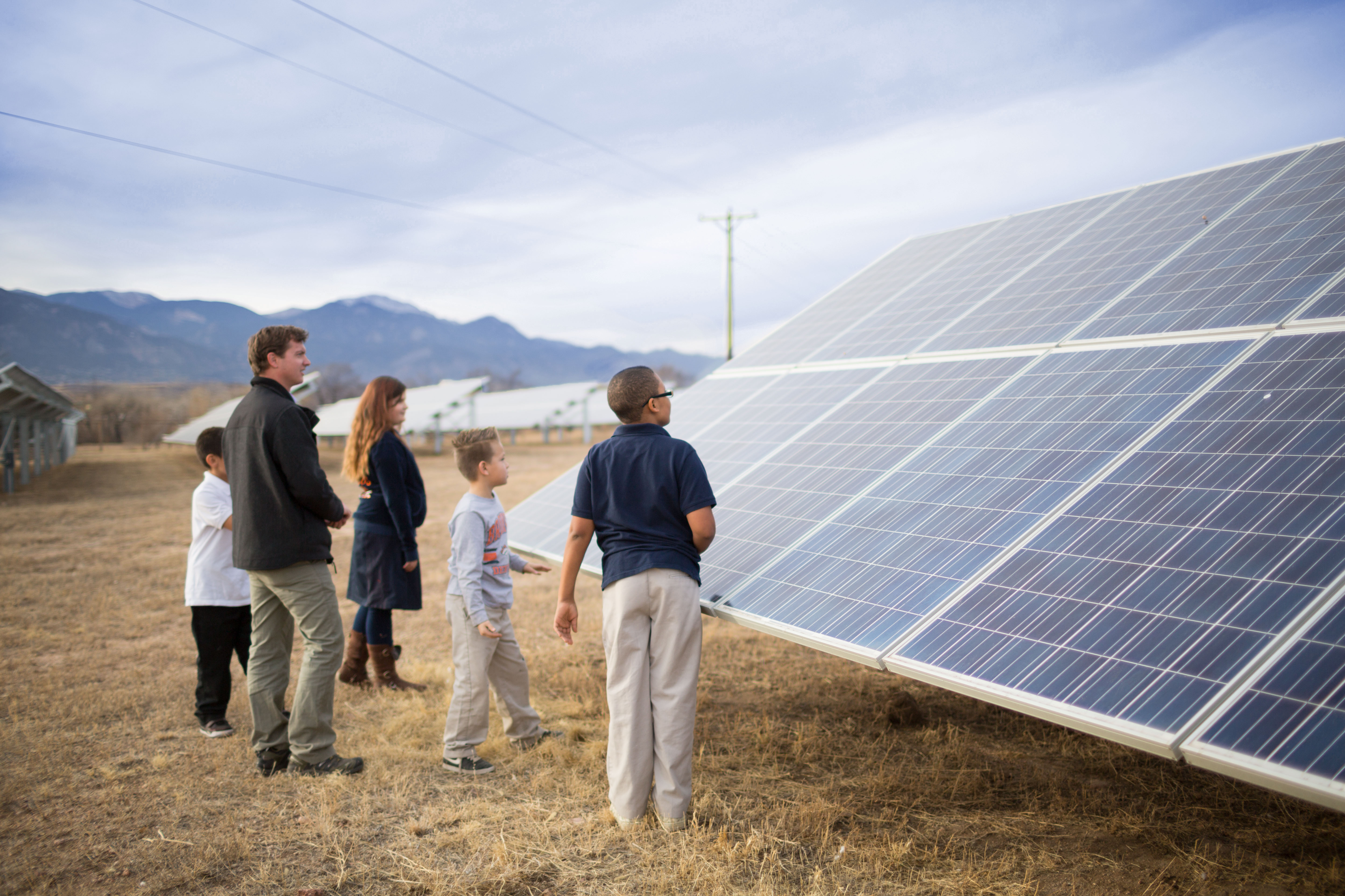 Group of people standing right by a solar panel