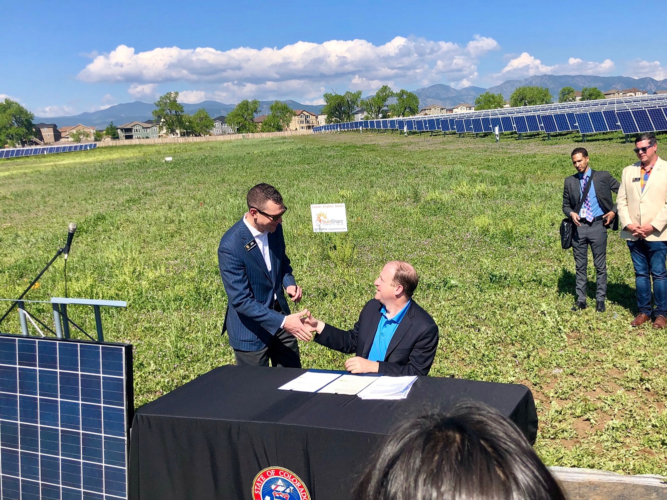 Two men shaking hands in solar panel field